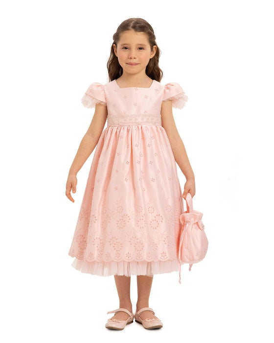 Young girl wearing a pink lace dress holding a matching handbag on a white background