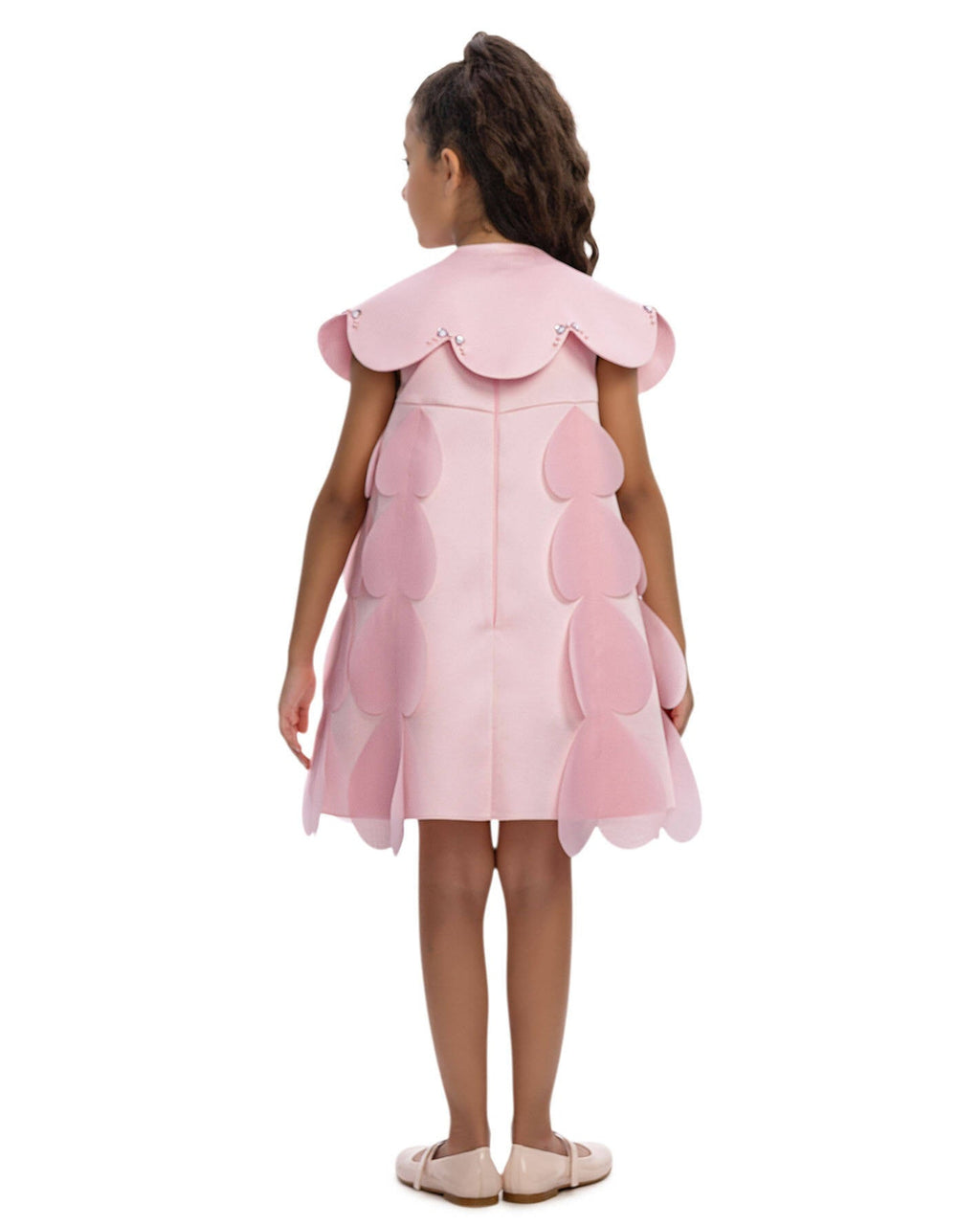 Young girl wearing a pink dress with layered skirt on a white background