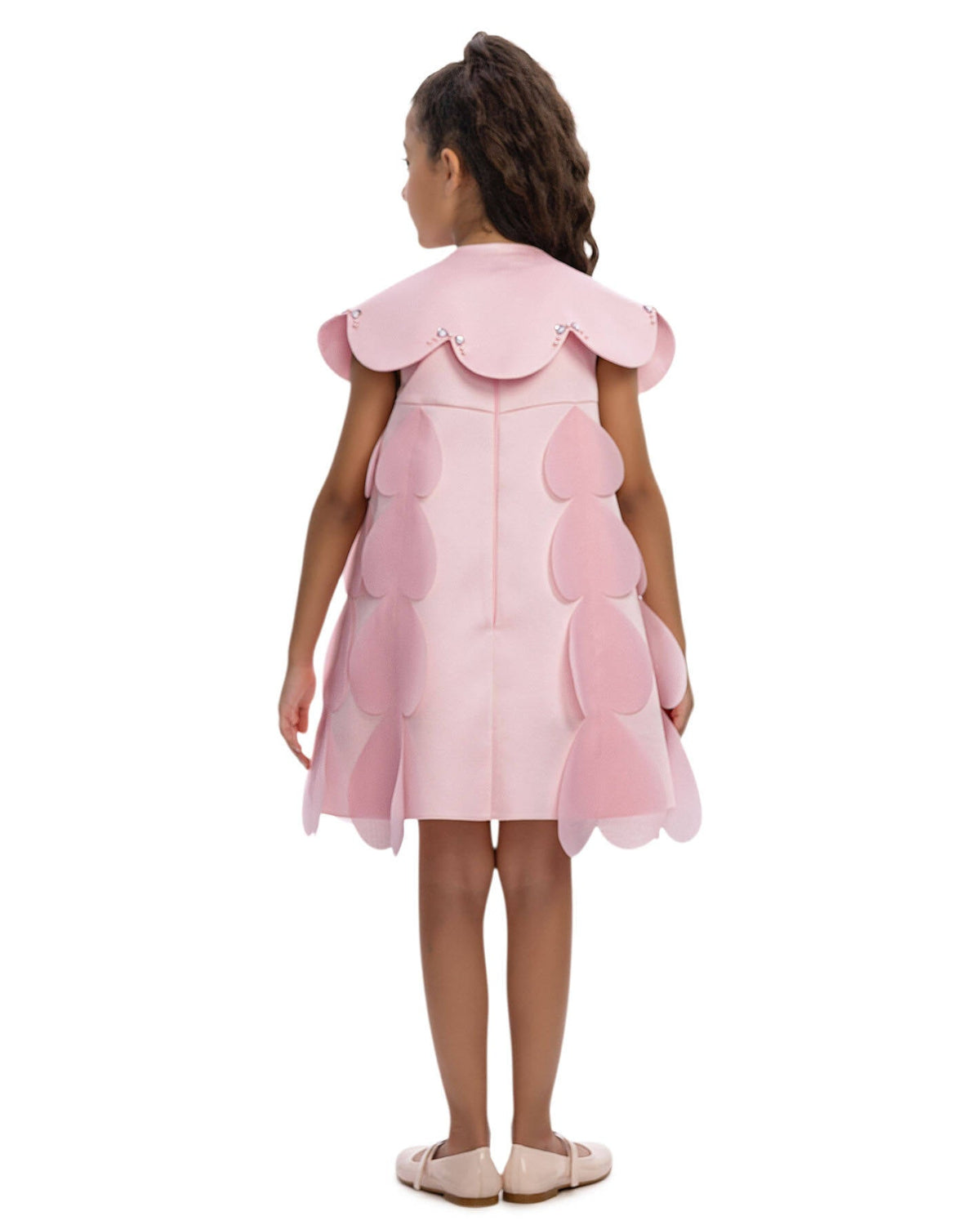 Young girl wearing a pink dress with layered skirt on a white background