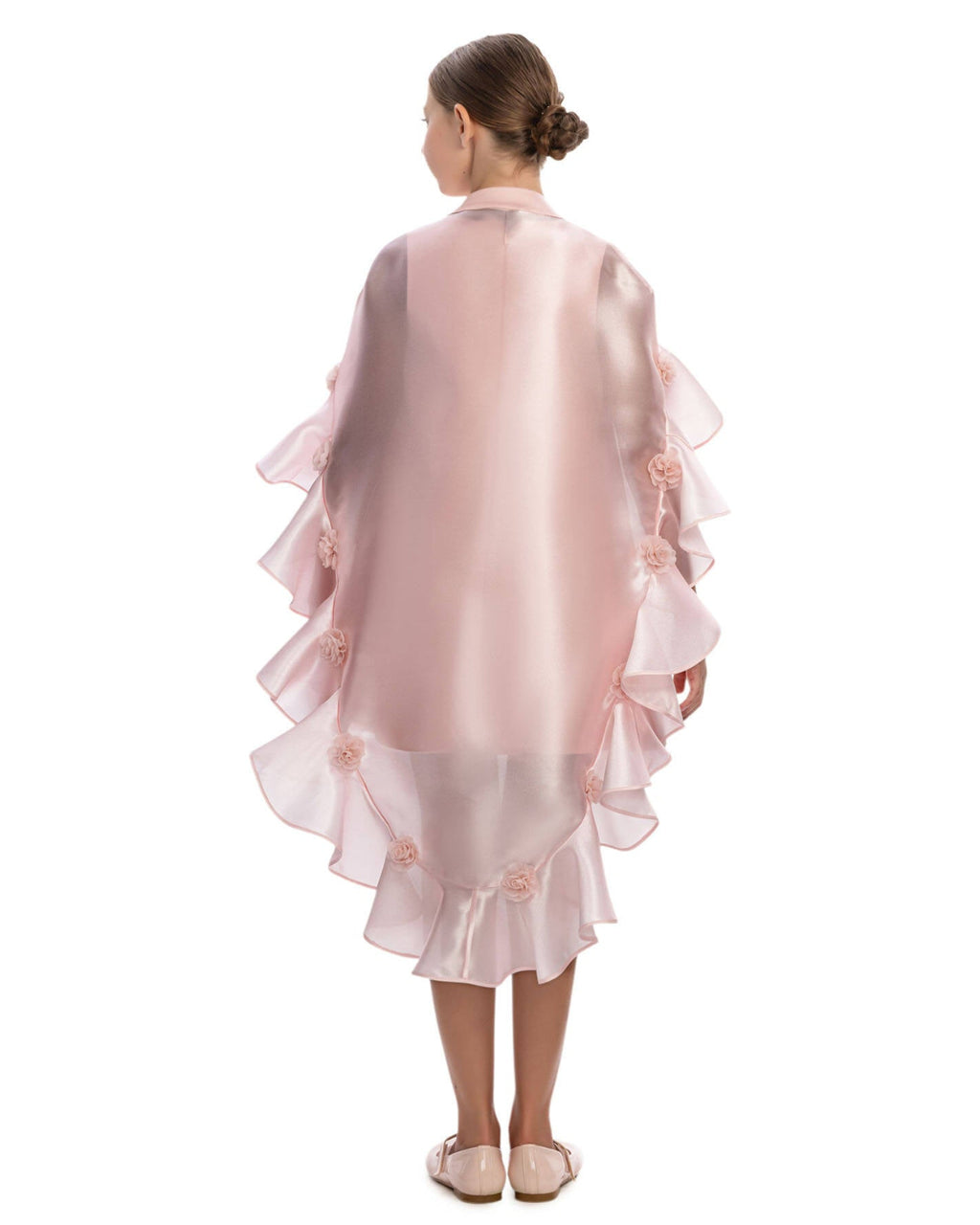 Young girl wearing a pink ruffled dress with floral details on a white background