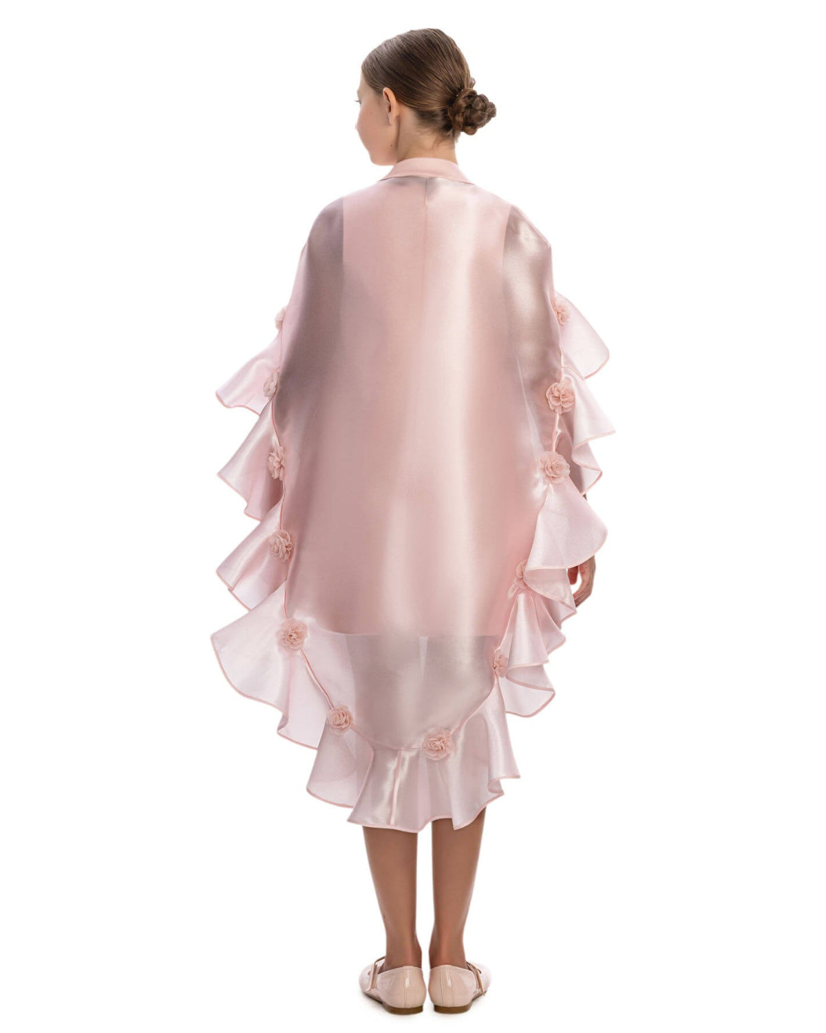 Young girl wearing a pink ruffled dress with floral details on a white background